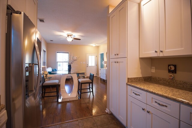 kitchen featuring stone counters, dark hardwood / wood-style floors, white cabinetry, ceiling fan, and stainless steel refrigerator with ice dispenser