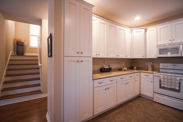 kitchen featuring light stone counters, white appliances, and white cabinets