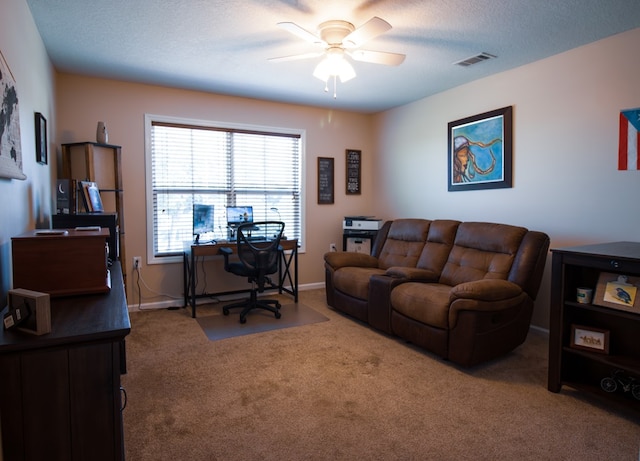 carpeted office featuring ceiling fan and a textured ceiling