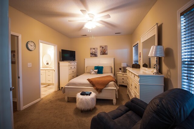 carpeted bedroom with ensuite bathroom, ceiling fan, and a textured ceiling