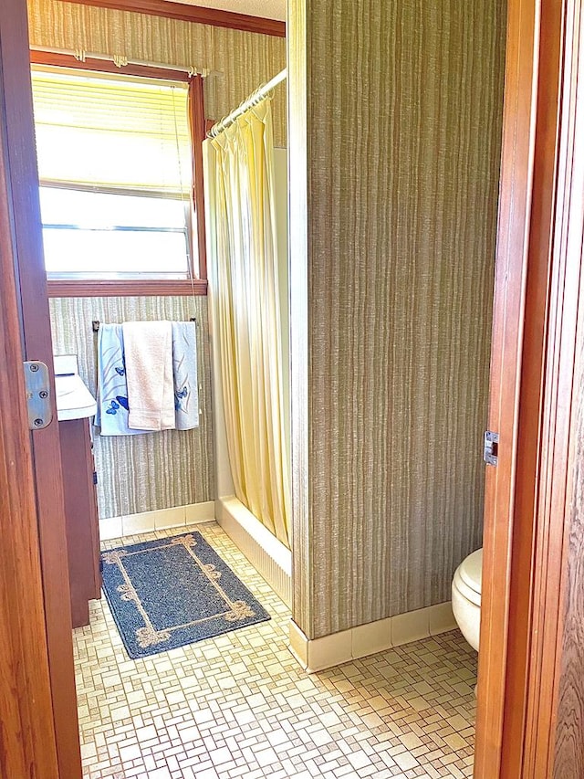 bathroom featuring toilet and curtained shower