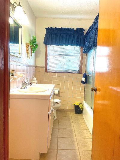 full bathroom featuring enclosed tub / shower combo, tile walls, vanity, tile patterned floors, and toilet