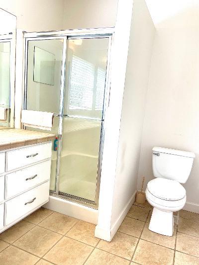 bathroom featuring vanity, toilet, tile patterned flooring, and a shower with door