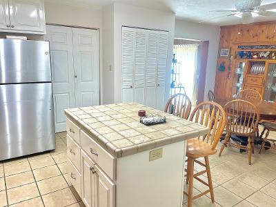 kitchen with stainless steel fridge, a kitchen bar, white cabinets, a kitchen island, and tile countertops