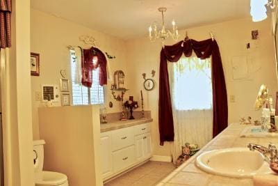 bathroom featuring tile patterned floors, toilet, a chandelier, and vanity