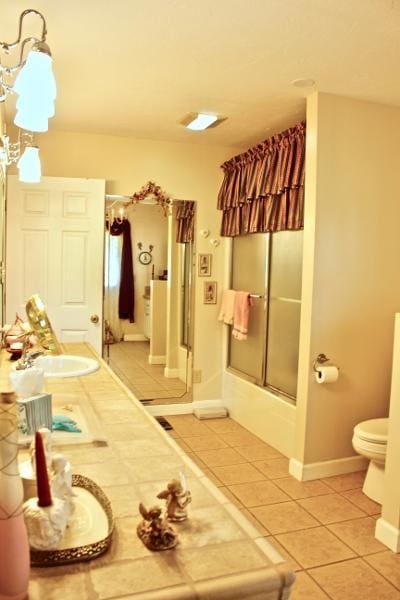 full bathroom featuring enclosed tub / shower combo, tile patterned floors, toilet, and vanity