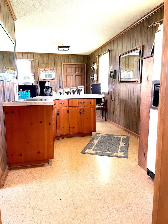 kitchen featuring wood walls, a textured ceiling, and kitchen peninsula