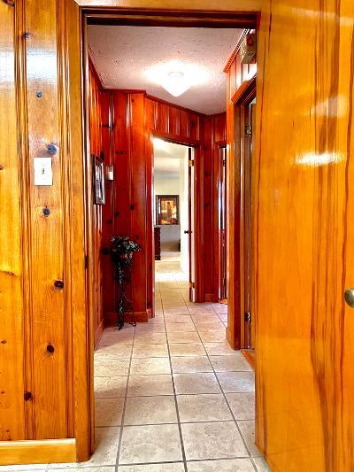 corridor with light tile patterned floors, a textured ceiling, and wood walls