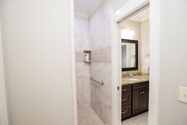 bathroom with ornamental molding, tile patterned flooring, tiled shower, and vanity