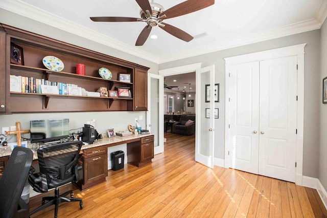 office area featuring built in desk, light wood finished floors, ornamental molding, a ceiling fan, and baseboards