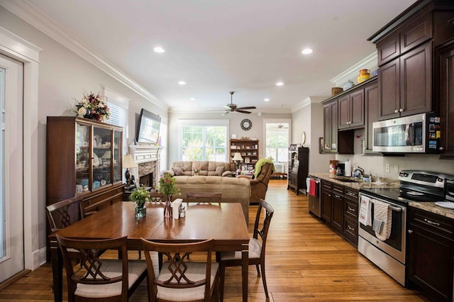 kitchen featuring dark brown cabinetry, a fireplace, appliances with stainless steel finishes, and light wood finished floors