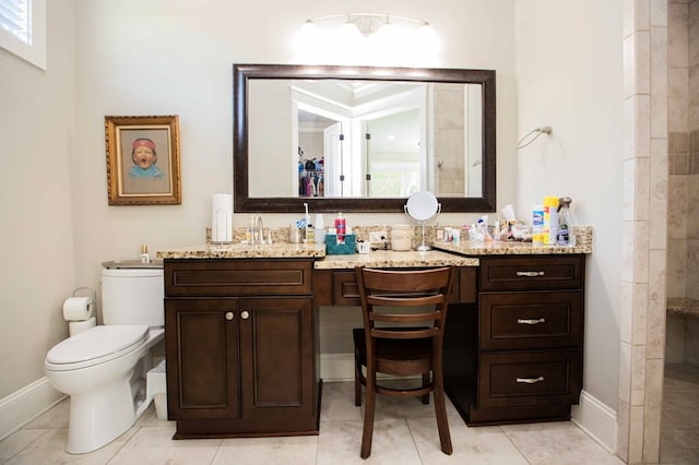 bathroom featuring toilet, tiled shower, vanity, and baseboards