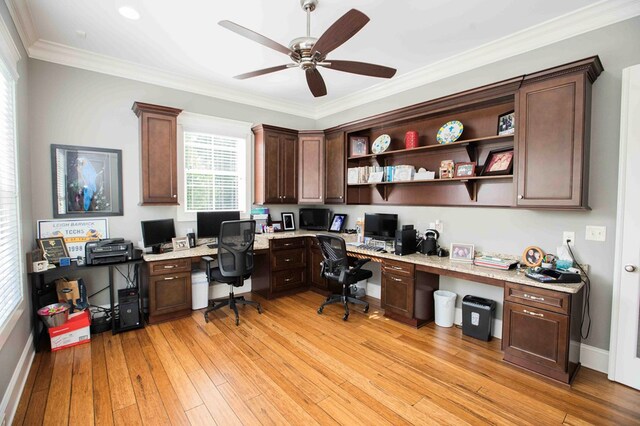 office area with light wood-style flooring, ornamental molding, built in study area, ceiling fan, and baseboards