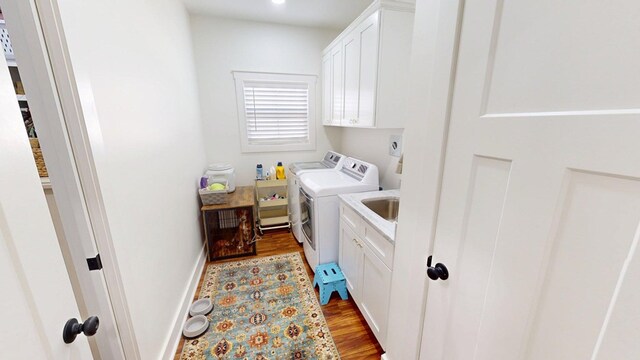 clothes washing area with a sink, wood finished floors, baseboards, independent washer and dryer, and cabinet space