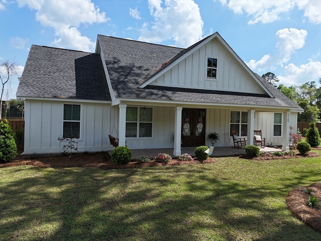 view of front of home featuring fence, covered porch, a front lawn, board and batten siding, and a shingled roof