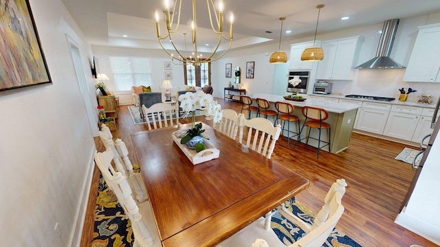 dining room with a chandelier, baseboards, wood finished floors, recessed lighting, and a tray ceiling