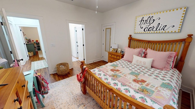 bedroom with baseboards, visible vents, and wood finished floors