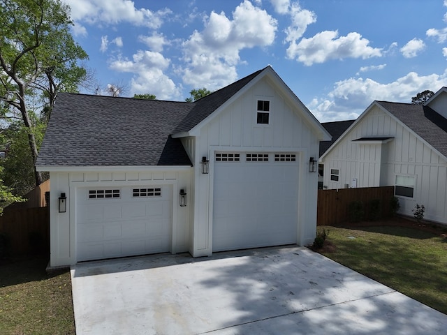 view of front of home with fence, a garage, concrete driveway, board and batten siding, and roof with shingles