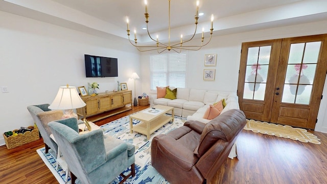 living area with wood finished floors, french doors, an inviting chandelier, and a raised ceiling