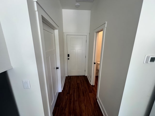 hallway featuring baseboards and dark wood-style flooring