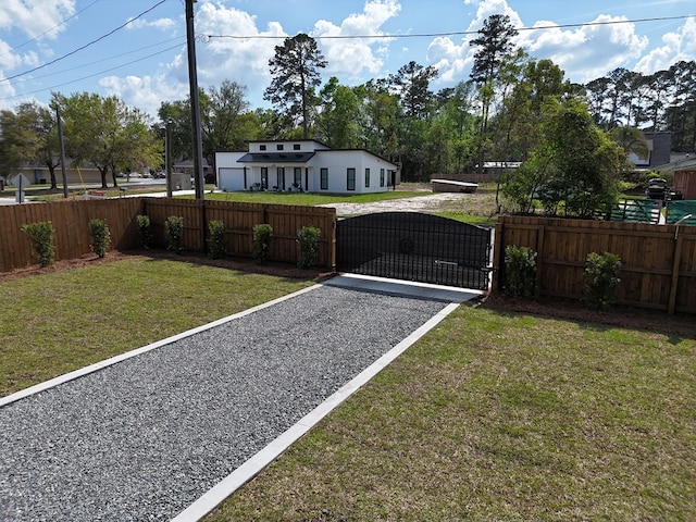 view of yard featuring gravel driveway, a gate, and fence