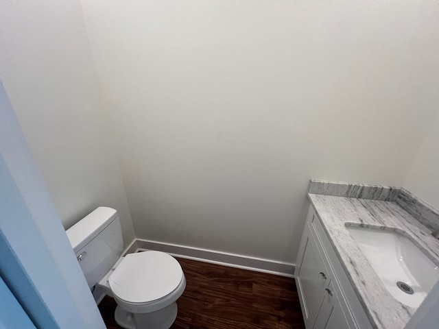 bathroom with toilet, vanity, baseboards, and wood finished floors