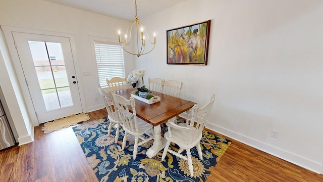 dining space featuring a healthy amount of sunlight, wood finished floors, baseboards, and an inviting chandelier