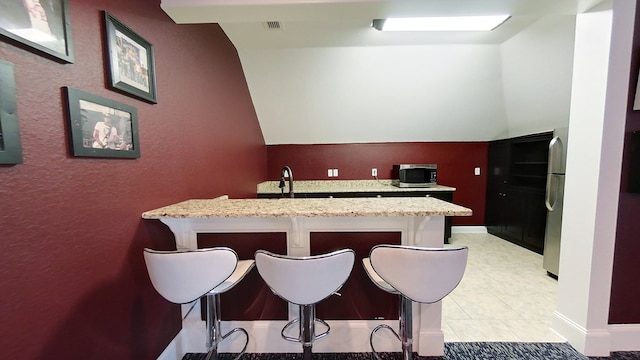 kitchen with light stone counters, a kitchen breakfast bar, kitchen peninsula, and appliances with stainless steel finishes