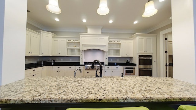 kitchen with ornamental molding, a breakfast bar area, double oven, and hanging light fixtures