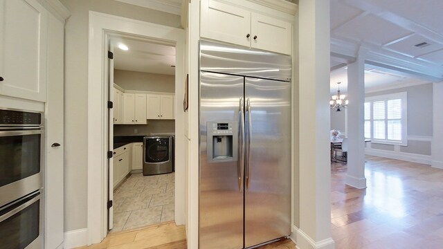 kitchen featuring an inviting chandelier, appliances with stainless steel finishes, washer / dryer, and white cabinets