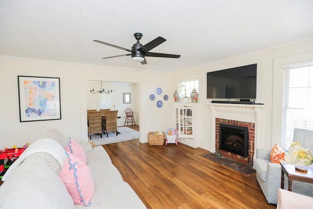 living area with ceiling fan, crown molding, a fireplace, and wood finished floors