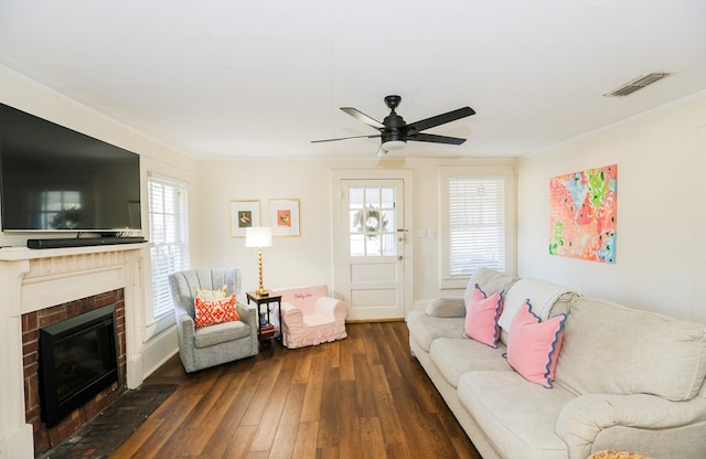 living room featuring a wealth of natural light, dark wood-type flooring, ornamental molding, and visible vents