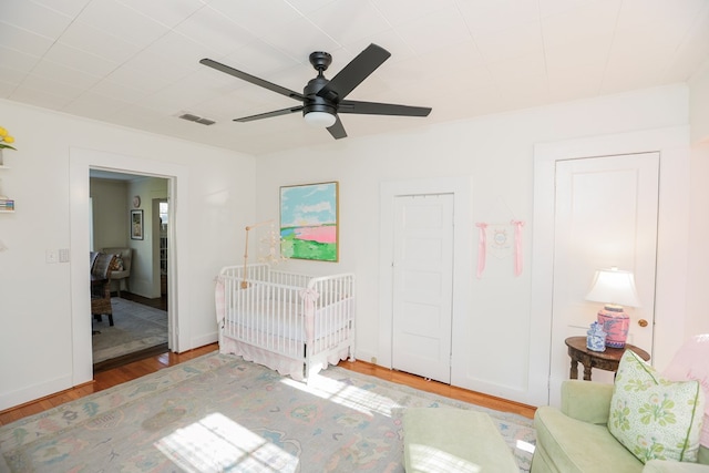 unfurnished bedroom with a ceiling fan, wood finished floors, visible vents, and baseboards