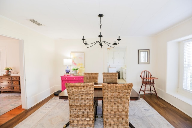 dining area with crown molding, a notable chandelier, visible vents, wood finished floors, and baseboards