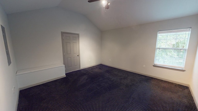 unfurnished room featuring dark colored carpet, vaulted ceiling, and ceiling fan