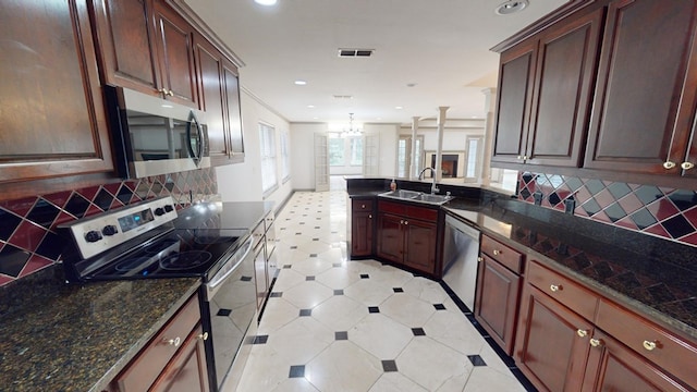 kitchen with sink, hanging light fixtures, dark stone countertops, appliances with stainless steel finishes, and backsplash