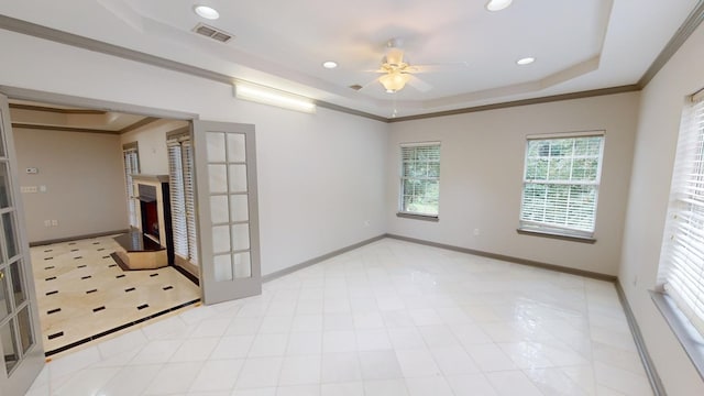 empty room featuring crown molding, ceiling fan, a tray ceiling, and french doors