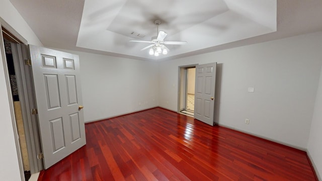 spare room featuring dark hardwood / wood-style floors, a raised ceiling, and ceiling fan