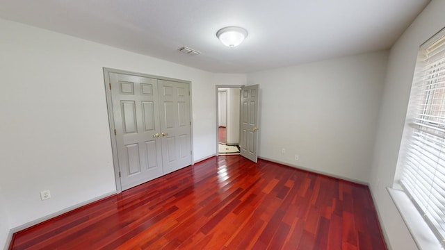 unfurnished bedroom with dark hardwood / wood-style floors and a closet