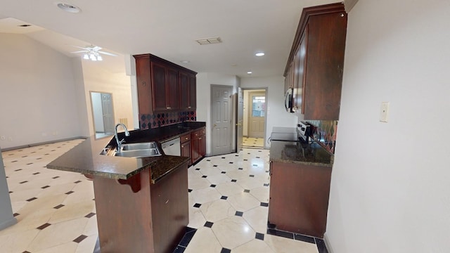 kitchen featuring sink, ceiling fan, stainless steel appliances, a kitchen bar, and kitchen peninsula