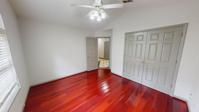 unfurnished bedroom featuring dark wood-type flooring, vaulted ceiling, a closet, and ceiling fan