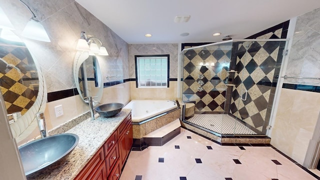 bathroom with vanity, independent shower and bath, and tile walls