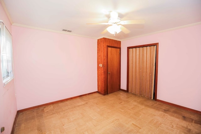 unfurnished bedroom featuring light parquet floors, ornamental molding, ceiling fan, and a closet