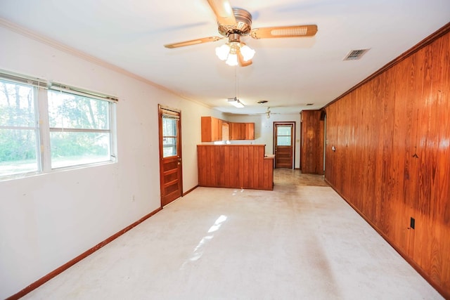 empty room featuring wooden walls, ornamental molding, and ceiling fan