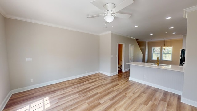 unfurnished living room featuring crown molding, sink, ceiling fan, and light hardwood / wood-style flooring