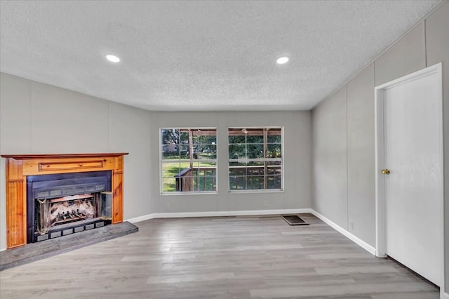 157 Quail Rdg, Moultrie, GA 31788 - unfurnished living room featuring a textured ceiling, wood finished floors, a fireplace with raised hearth, and recessed lighting