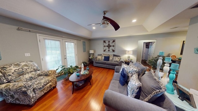 living room with hardwood / wood-style floors, a raised ceiling, ceiling fan, and french doors