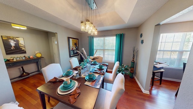 dining room with a raised ceiling, a notable chandelier, and dark hardwood / wood-style flooring