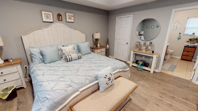 bedroom featuring ensuite bathroom and light hardwood / wood-style flooring