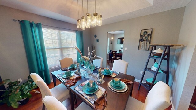 dining space with a raised ceiling, hardwood / wood-style floors, and a chandelier